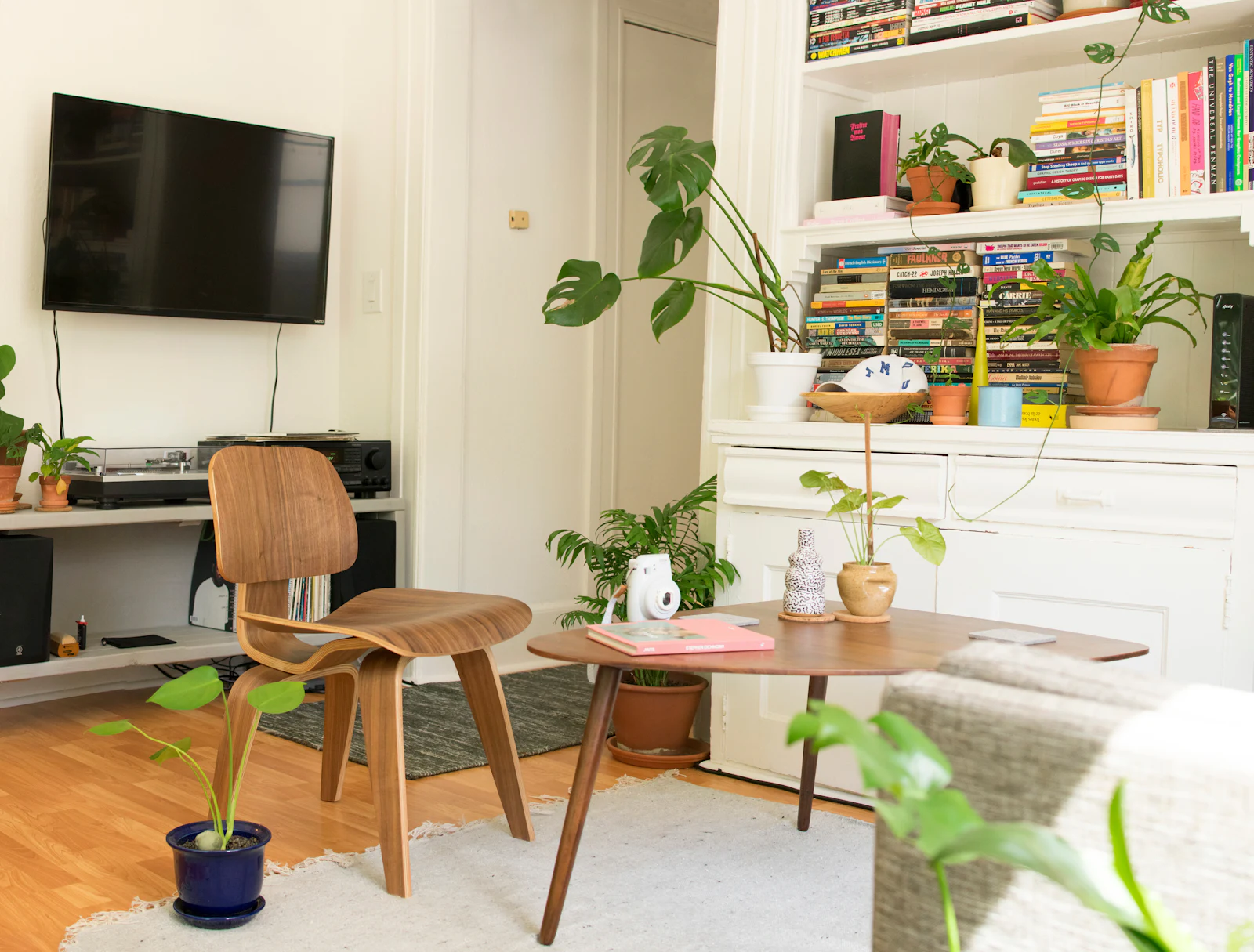 Living room with bookshelves, a work corner, plants and bentwood chairs
