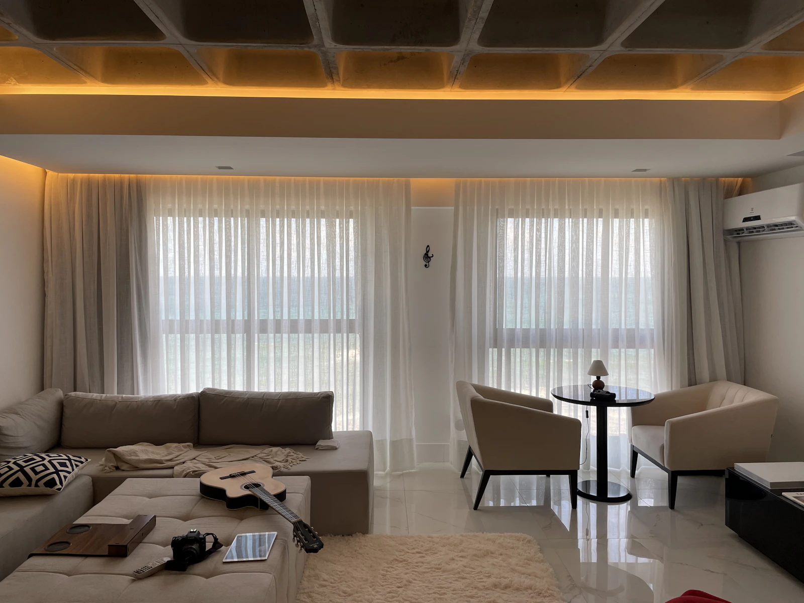 Bright living room with white walls, sheer curtains and a grey sofa