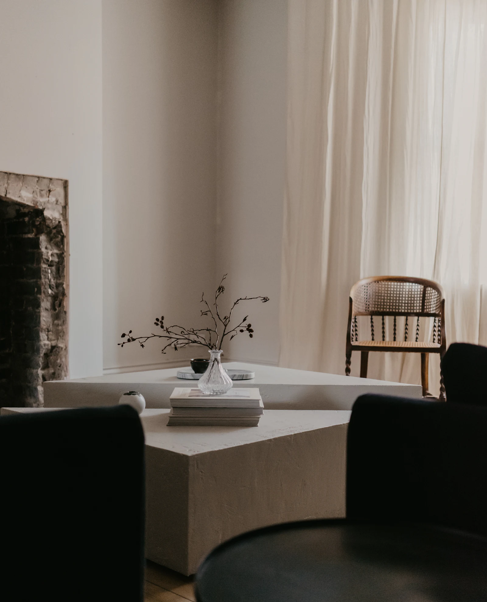 White interior with a low table, a branch in a glass vase and a wooden chair