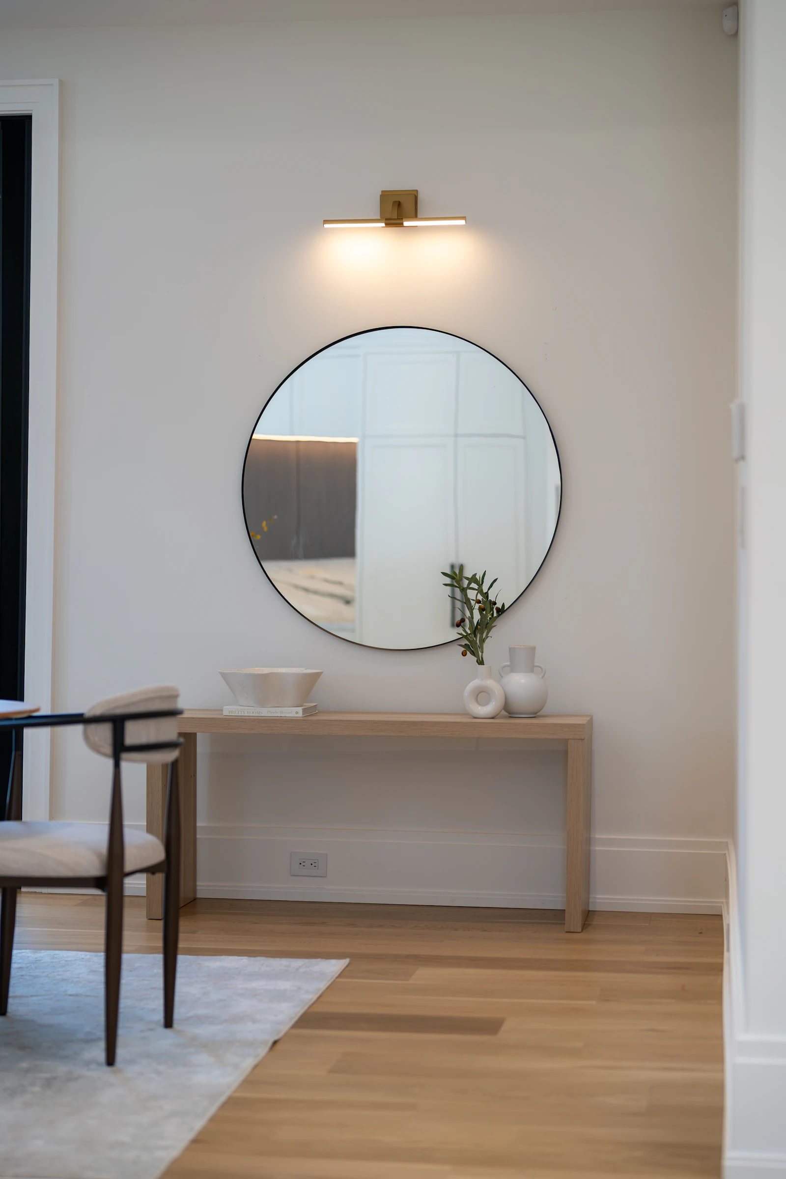 Round mirror above a slim wooden console