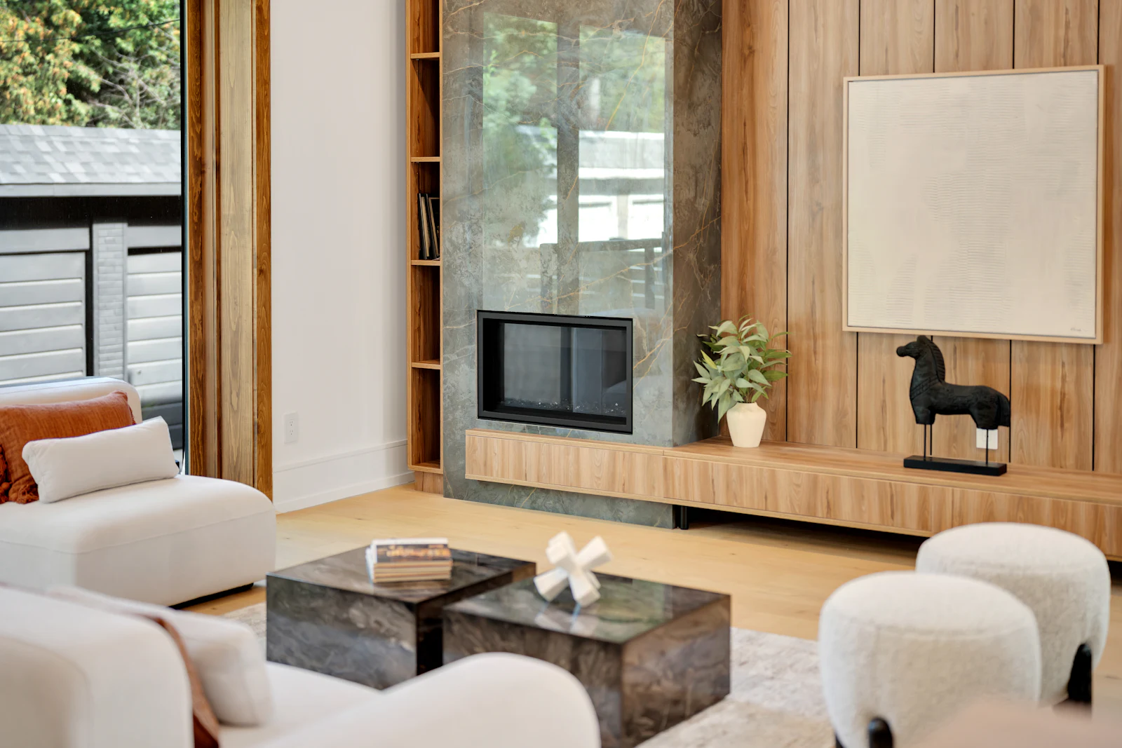 Living room with a stone fireplace, warm wood panelling and soft cream lounge chairs