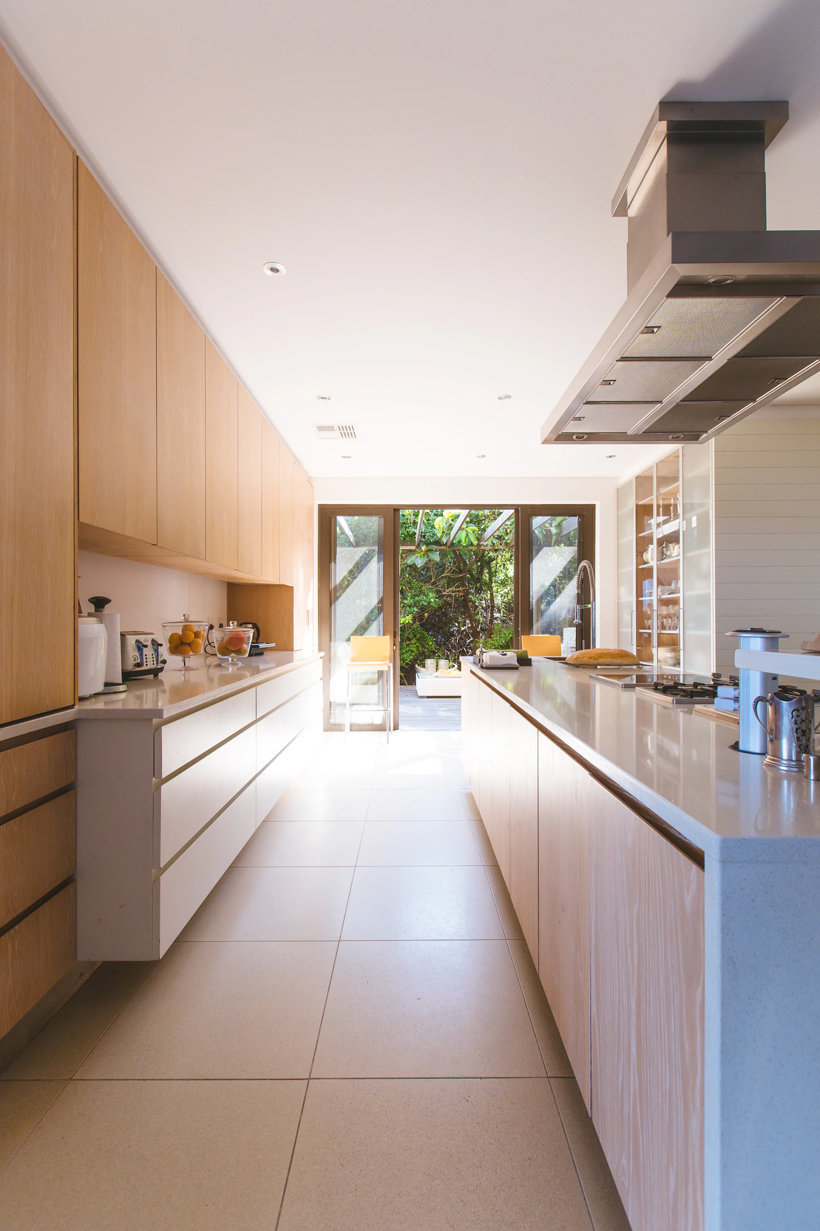 Long bright galley kitchen with pale wood cabinets