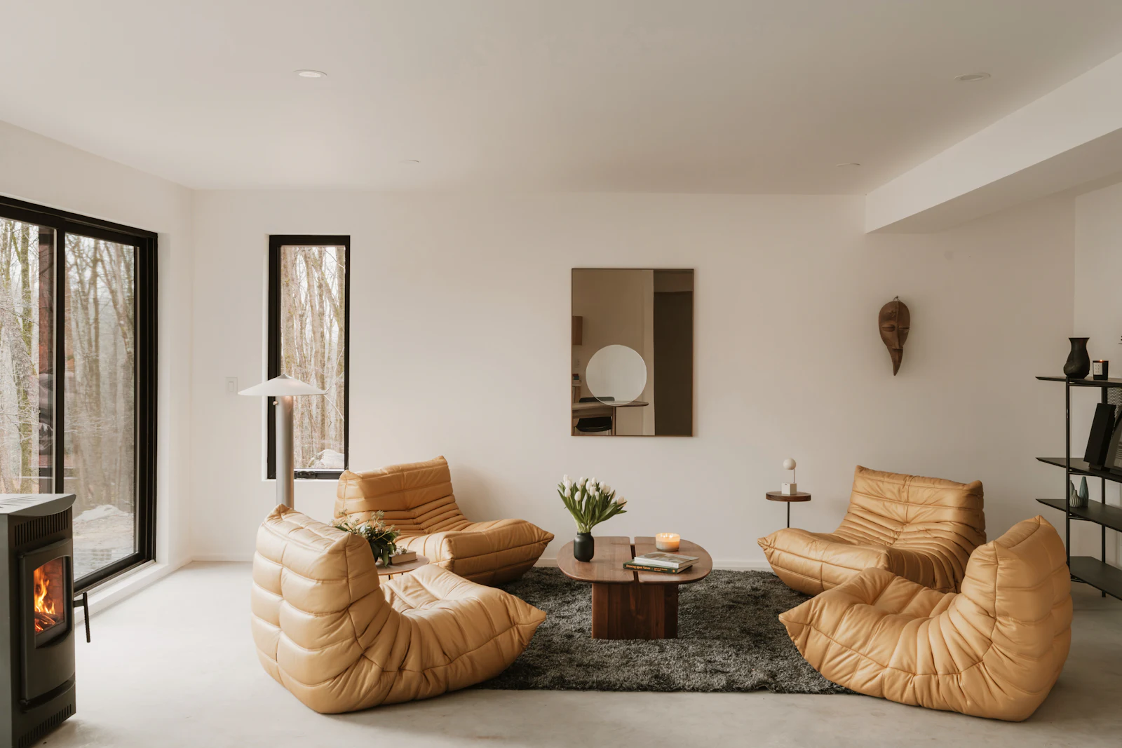 Bright room with low cognac leather lounge chairs and a wood stove