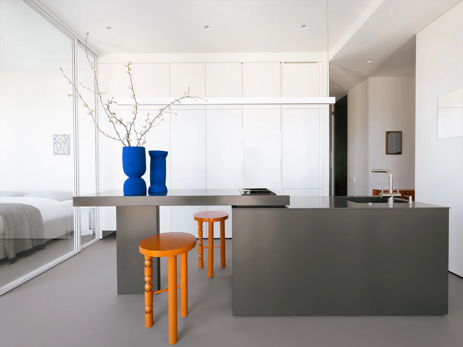 Minimalist kitchen island with cobalt vases and orange wooden stools