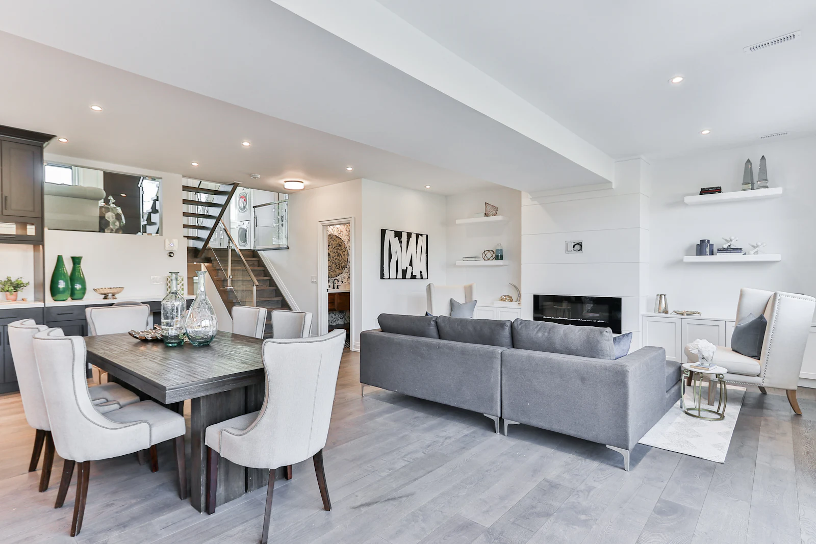 Open-plan dining area with white upholstered chairs and a grey sofa