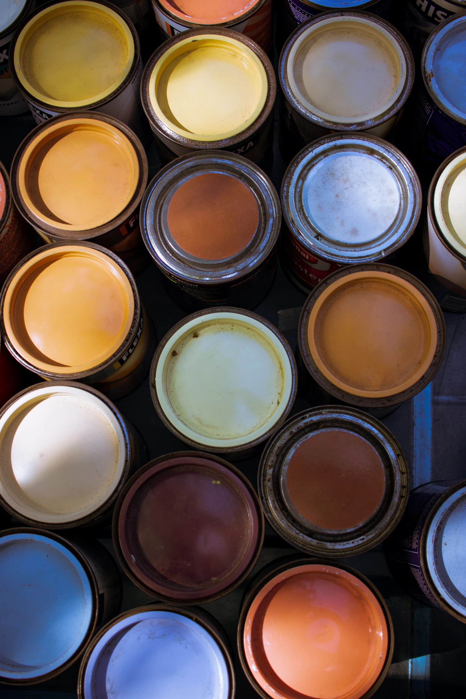 Open tins of paint in many colours seen from above