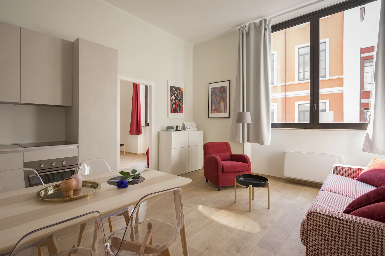Compact open-plan living and kitchen area with a red accent chair
