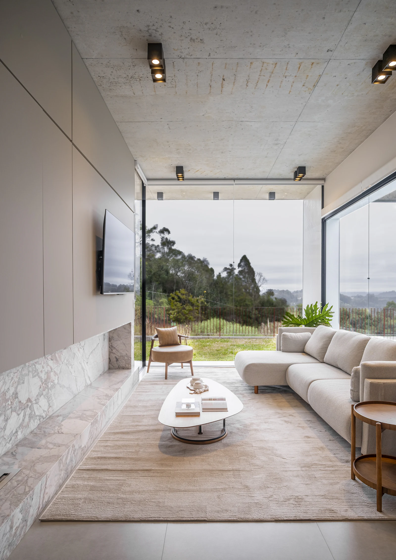 Living room with floor-to-ceiling windows framing a green landscape