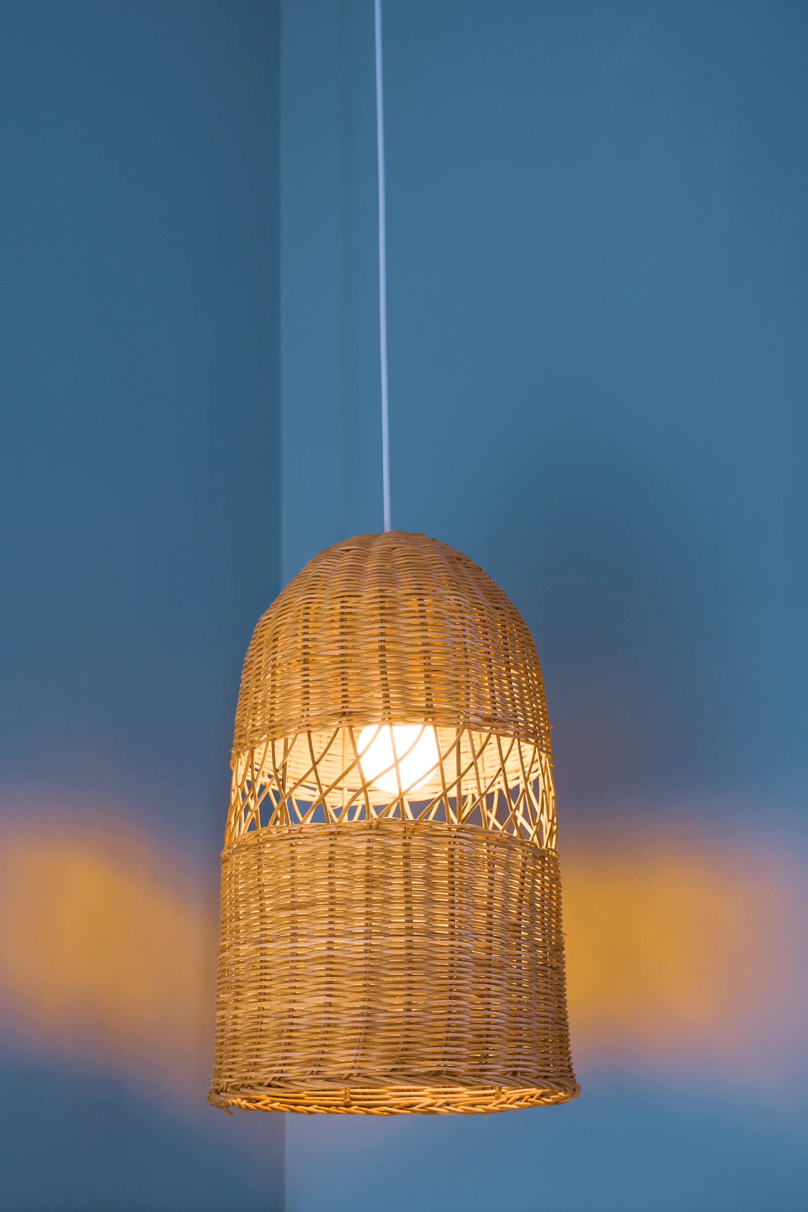 Wicker pendant light hanging against a blue wall